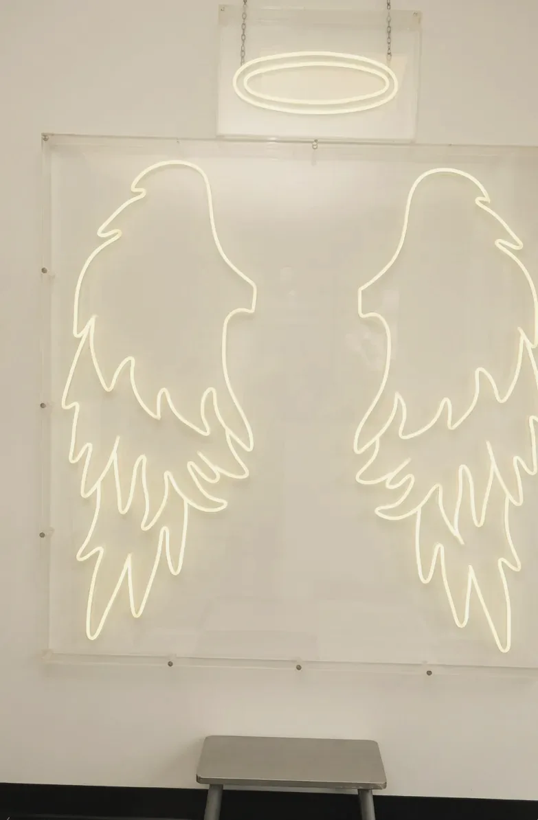 Glowing neon angel wings and halo on the studio wall